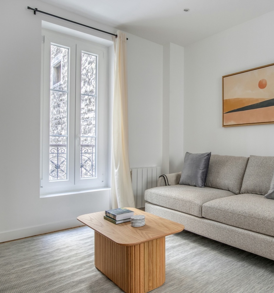 A bright living room with an empty floor spot, coffee table, and ceiling corner